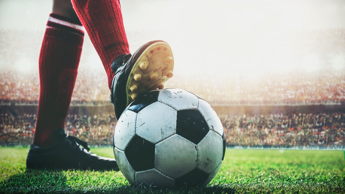 feet of soccer player tread on soccer ball for kick-off in the stadium